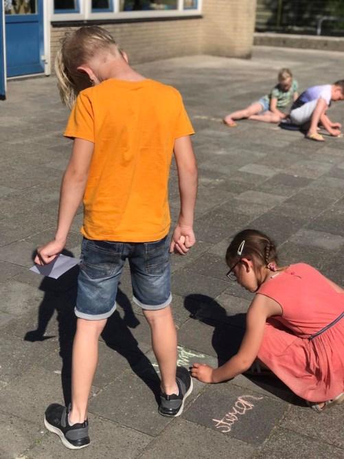 Kinderen tekenen met krijt op het schoolplein van de Prins Willem Alexanderschool in Ophemert. Kinderen tekenen met krijt op het schoolplein van de Prins Willem Alexanderschool in Ophemert.