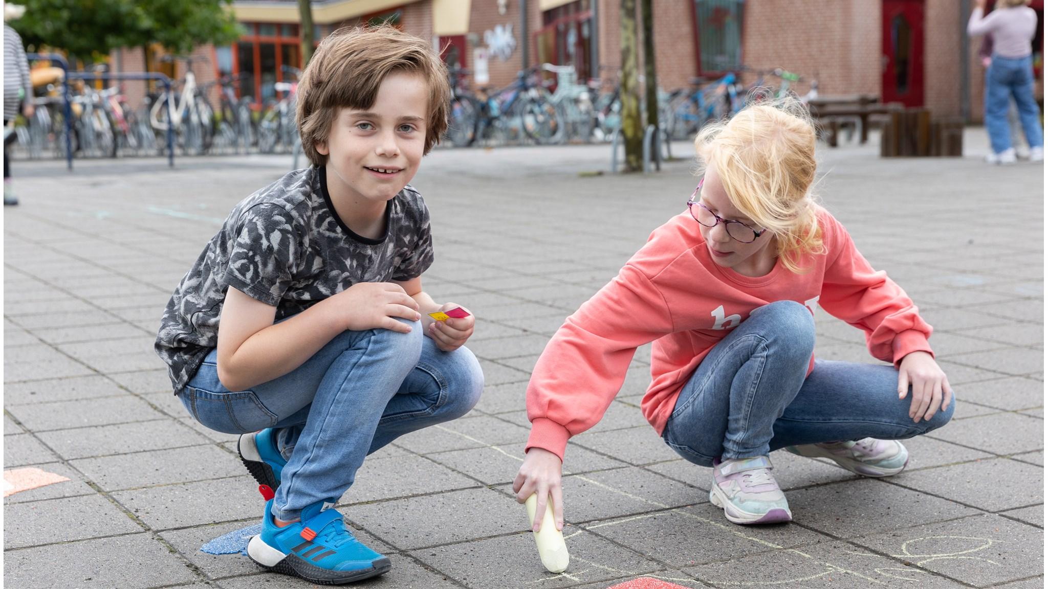 Kinderen tekenen met krijt op het schoolplein van IKC De Inktvis in Dirksland. Kinderen tekenen met krijt op het schoolplein van IKC De Inktvis in Dirksland.