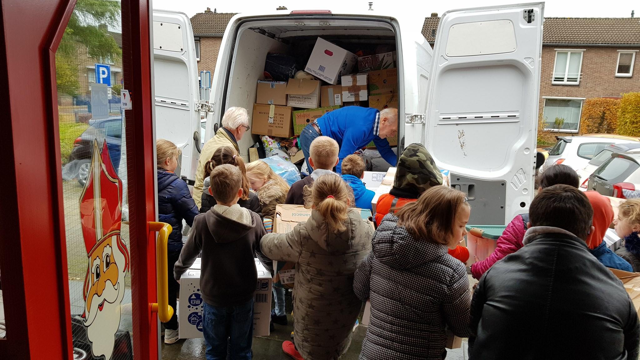 Kinderen van Basisschool De Bolster in Nuth helpen bij het inladen van dozen in een bus. Kinderen van Basisschool De Bolster in Nuth helpen bij het inladen van dozen in een bus.