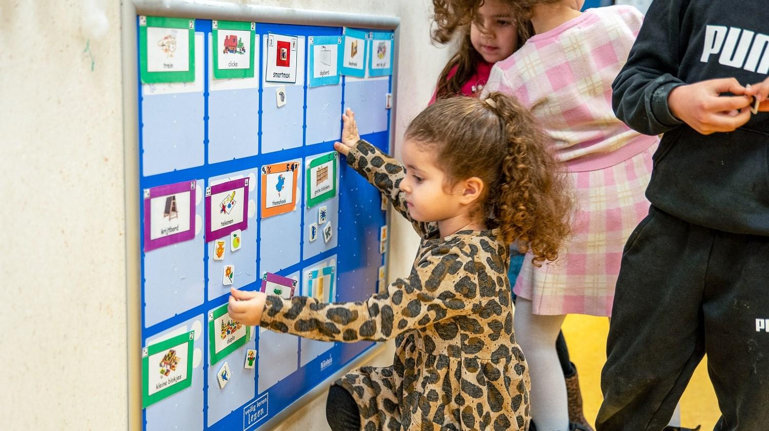 Kinderen van basisschool Ikra in Dordrecht spelen en leren met een bord vol afbeeldingen.