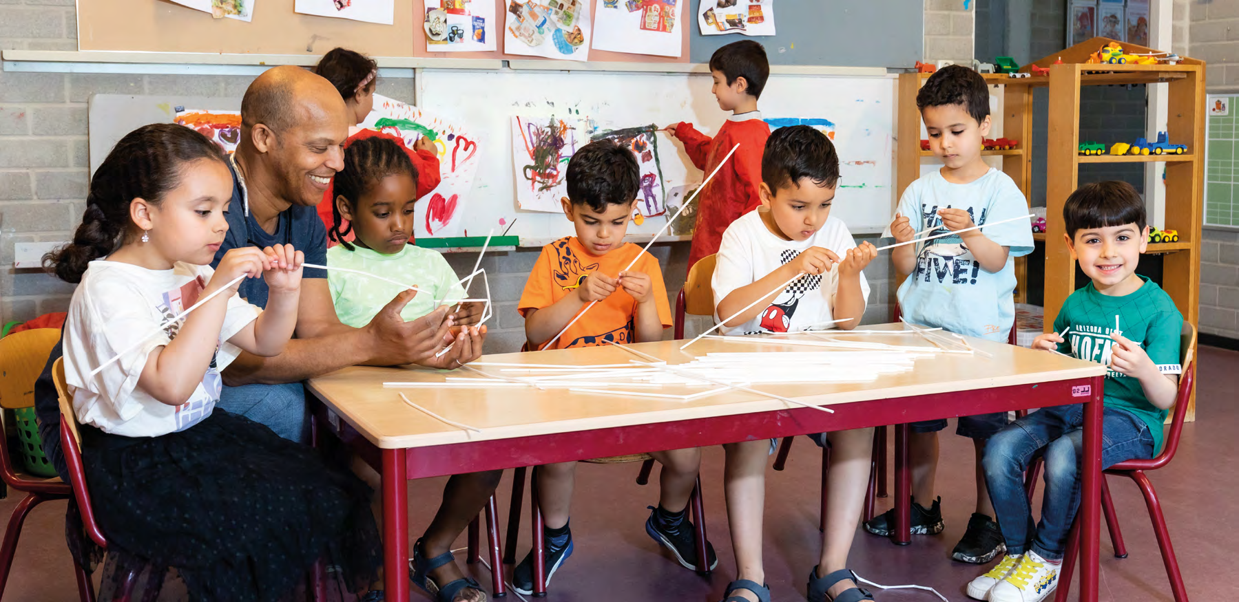 Kinderen van CBS Mozaïek in Rotterdam zijn samen bezig met knutselen aan een lange tafel.