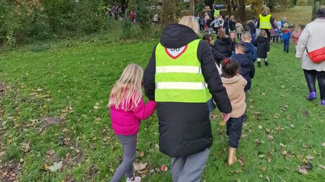 Kinderen van Communityschool De Kameleon in Zwanenburg lopen samen met een begeleider naar het schoolplein.