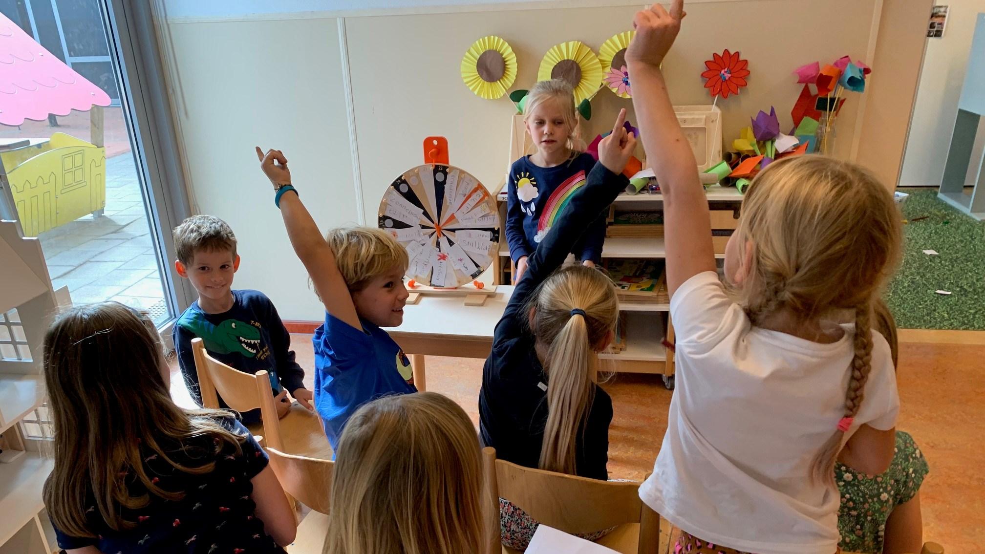 Kinderen van De Brug in Aalsmeer steken enthousiast hun handen op tijdens een activiteit.