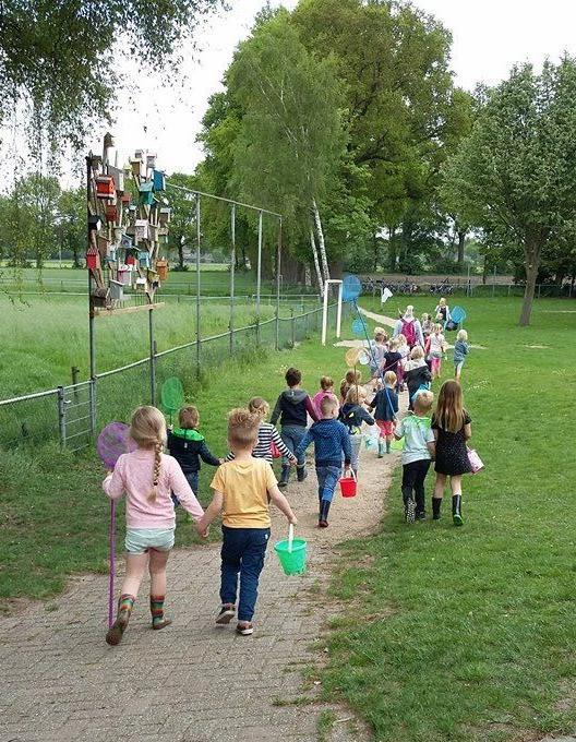 Kinderen van de Dorpsschool Halle wandelen naar het schoolplein met vangnetten en emmers. Kinderen van de Dorpsschool Halle wandelen naar het schoolplein met vangnetten en emmers.