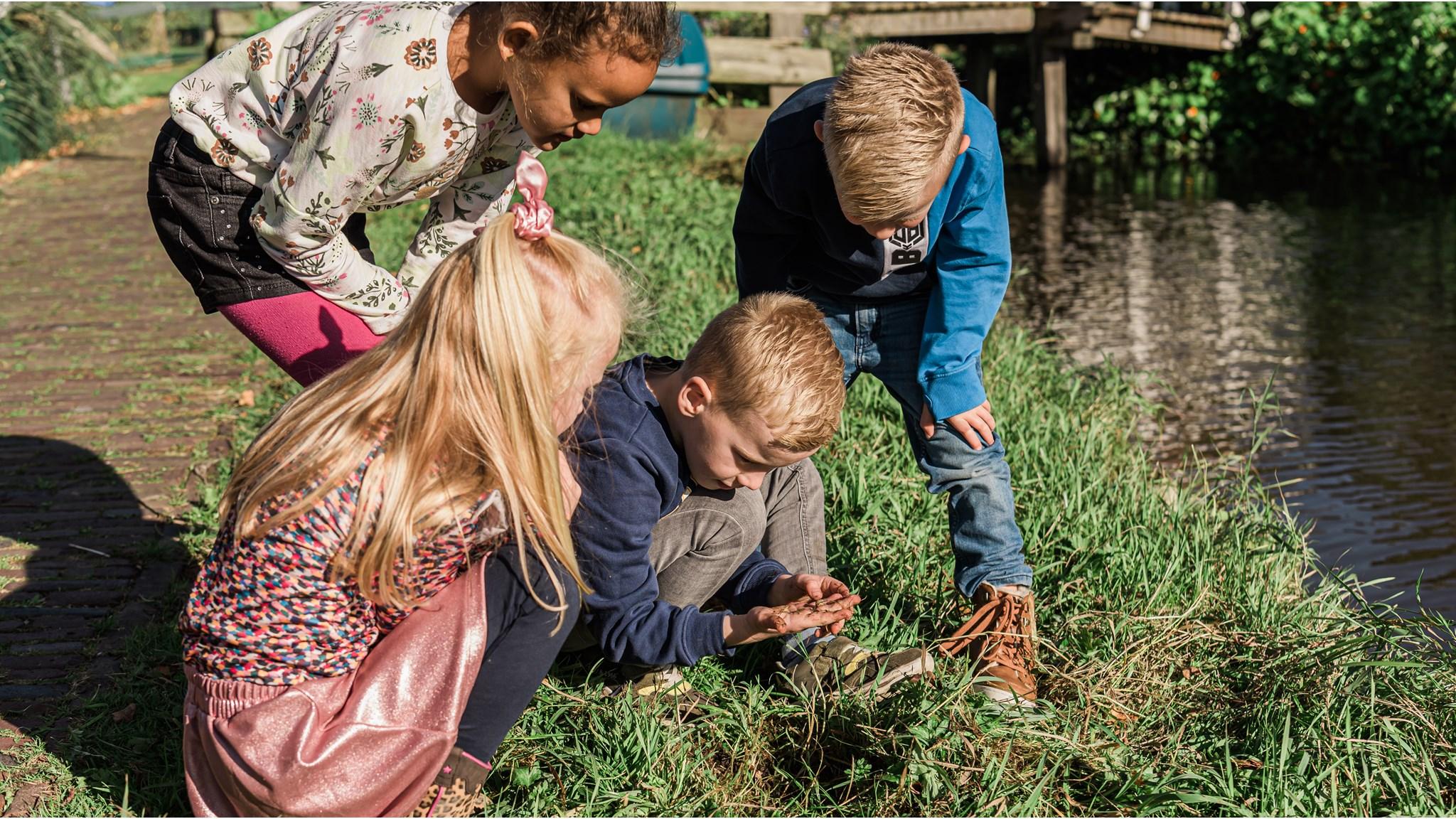 Kinderen van De Rietlanden in Marken ontdekken de natuur aan de oever van een waterweg.