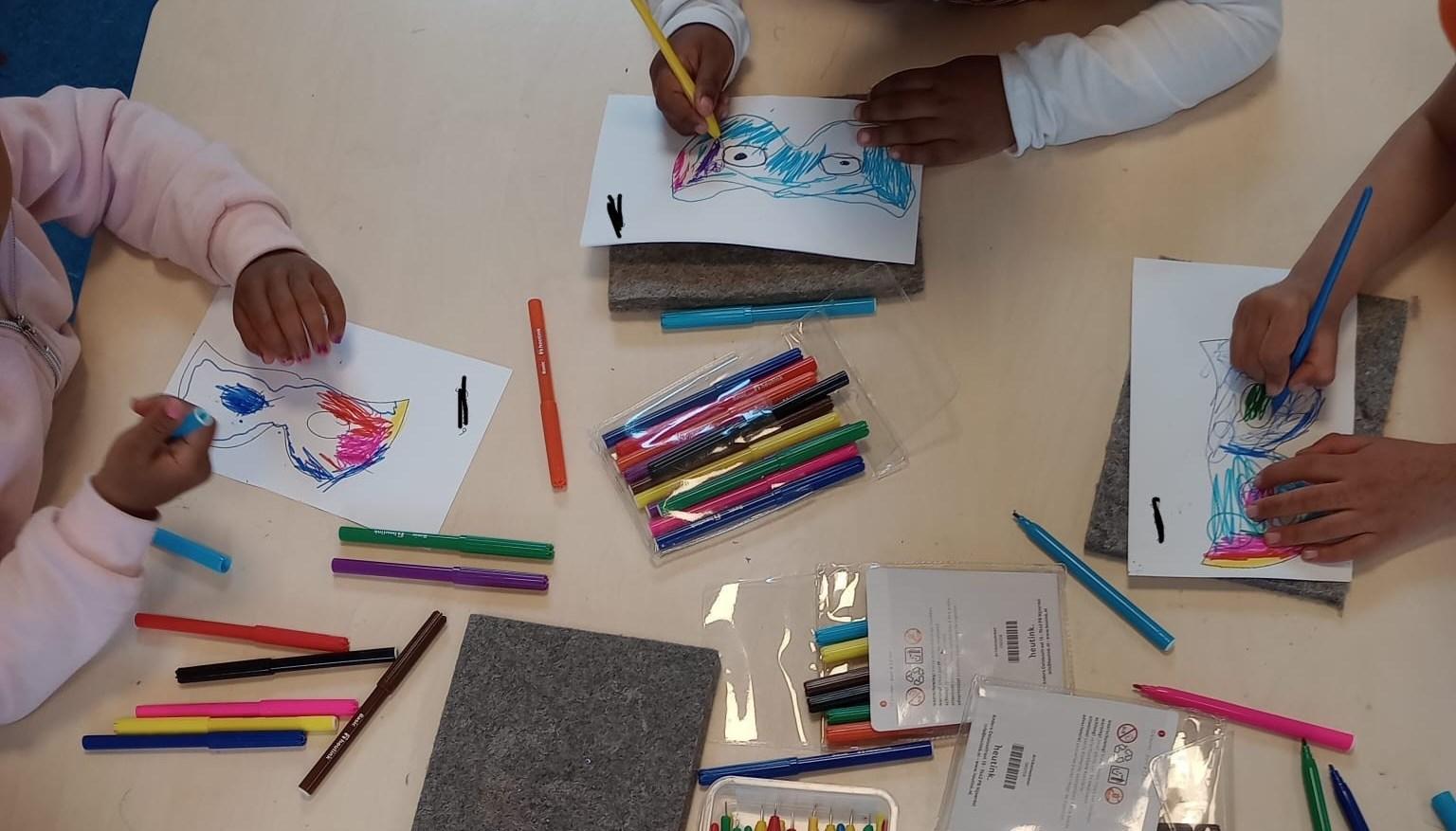 Kinderen van De Toermalijn in Rotterdam kleuren en tekenen creatief aan een tafel. Kinderen van De Toermalijn in Rotterdam kleuren en tekenen creatief aan een tafel.