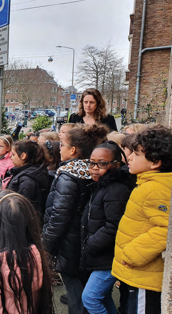 Kinderen van De Vlierboom in Den Haag wachten buiten met een docent voor de school. Kinderen van De Vlierboom in Den Haag wachten buiten met een docent voor de school.