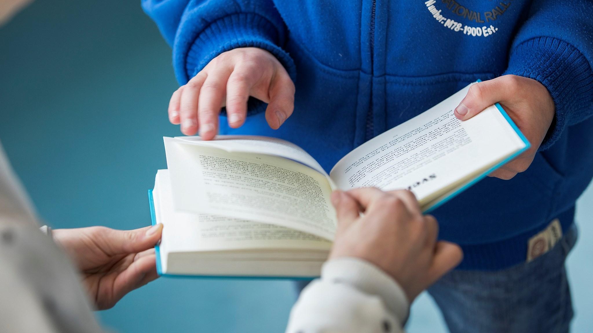 Kinderen van De Wilakkers in Eindhoven kijken samen naar een boek. Kinderen van De Wilakkers in Eindhoven kijken samen naar een boek.