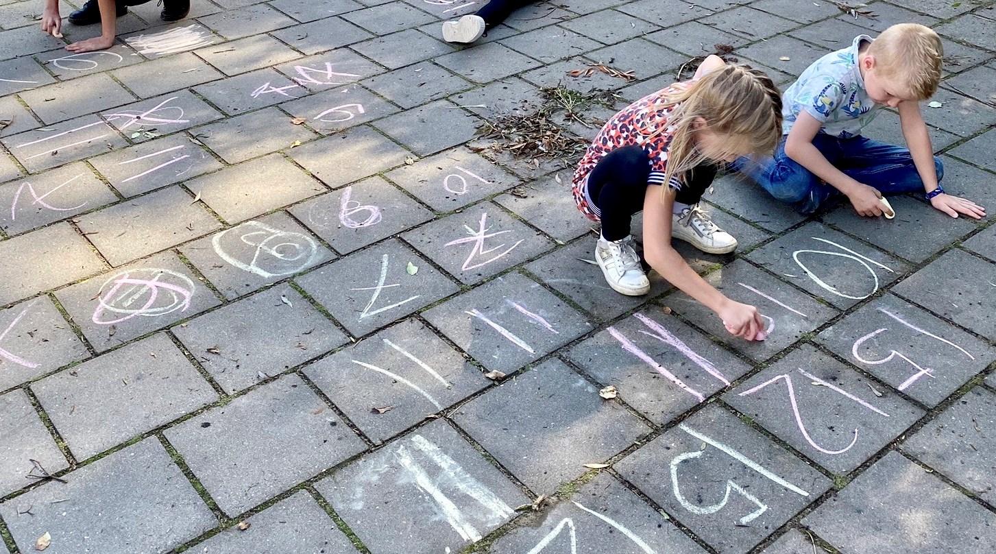 Kinderen van Integraal Kind Centrum Het Klokhuis in Duiven spelen met krijt op het schoolplein. Kinderen van Integraal Kind Centrum Het Klokhuis in Duiven spelen met krijt op het schoolplein.
