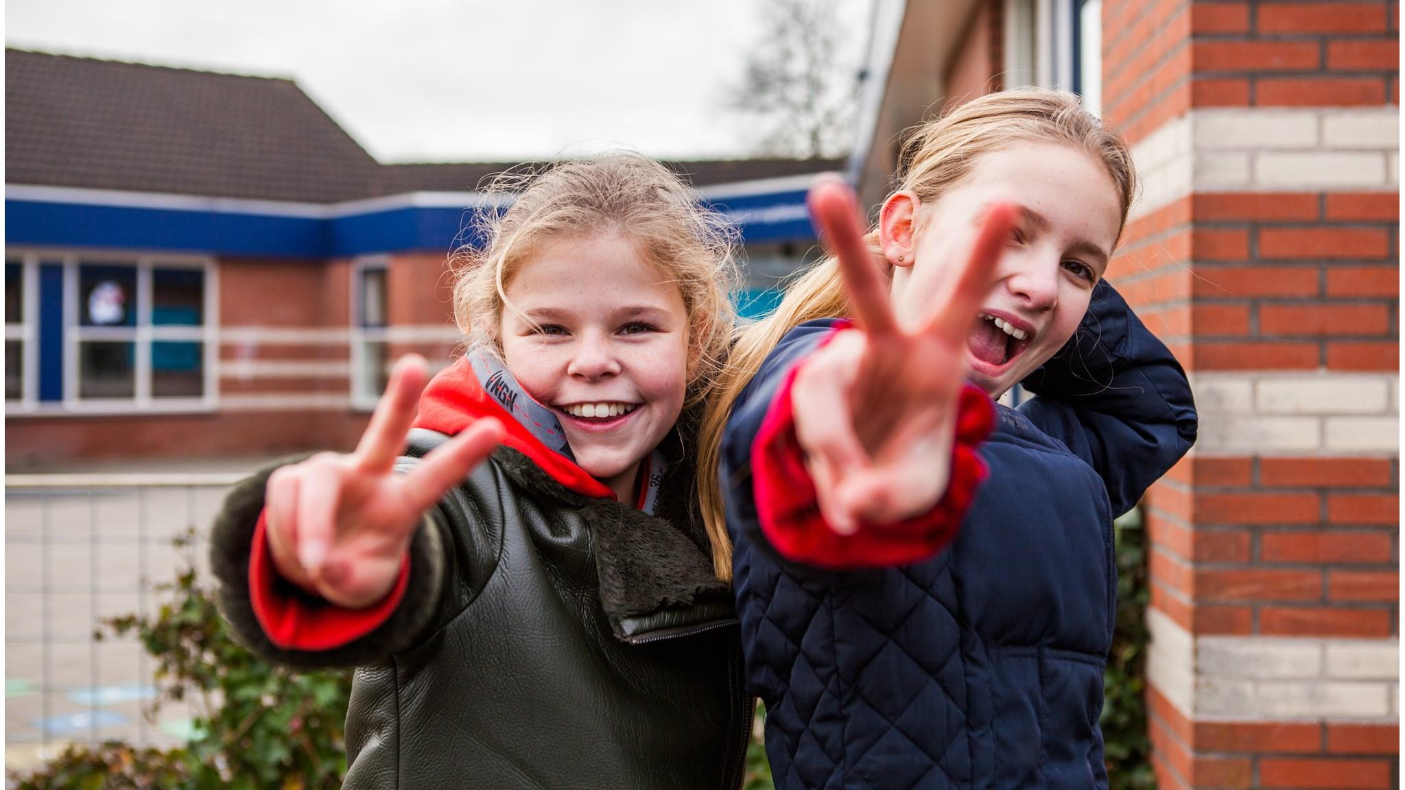 Kinderen van Kids College in Wilnis die vrolijk met de vrede-teken poseren op het schoolplein. Kinderen van Kids College in Wilnis die vrolijk met de vrede-teken poseren op het schoolplein.