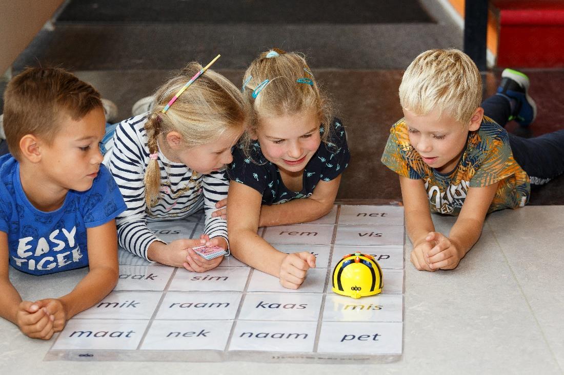 Kinderen van Openbare Basisschool De Kern in Ede spelen met een robot op de vloertegels met letters. Kinderen van Openbare Basisschool De Kern in Ede spelen met een robot op de vloertegels met letters.