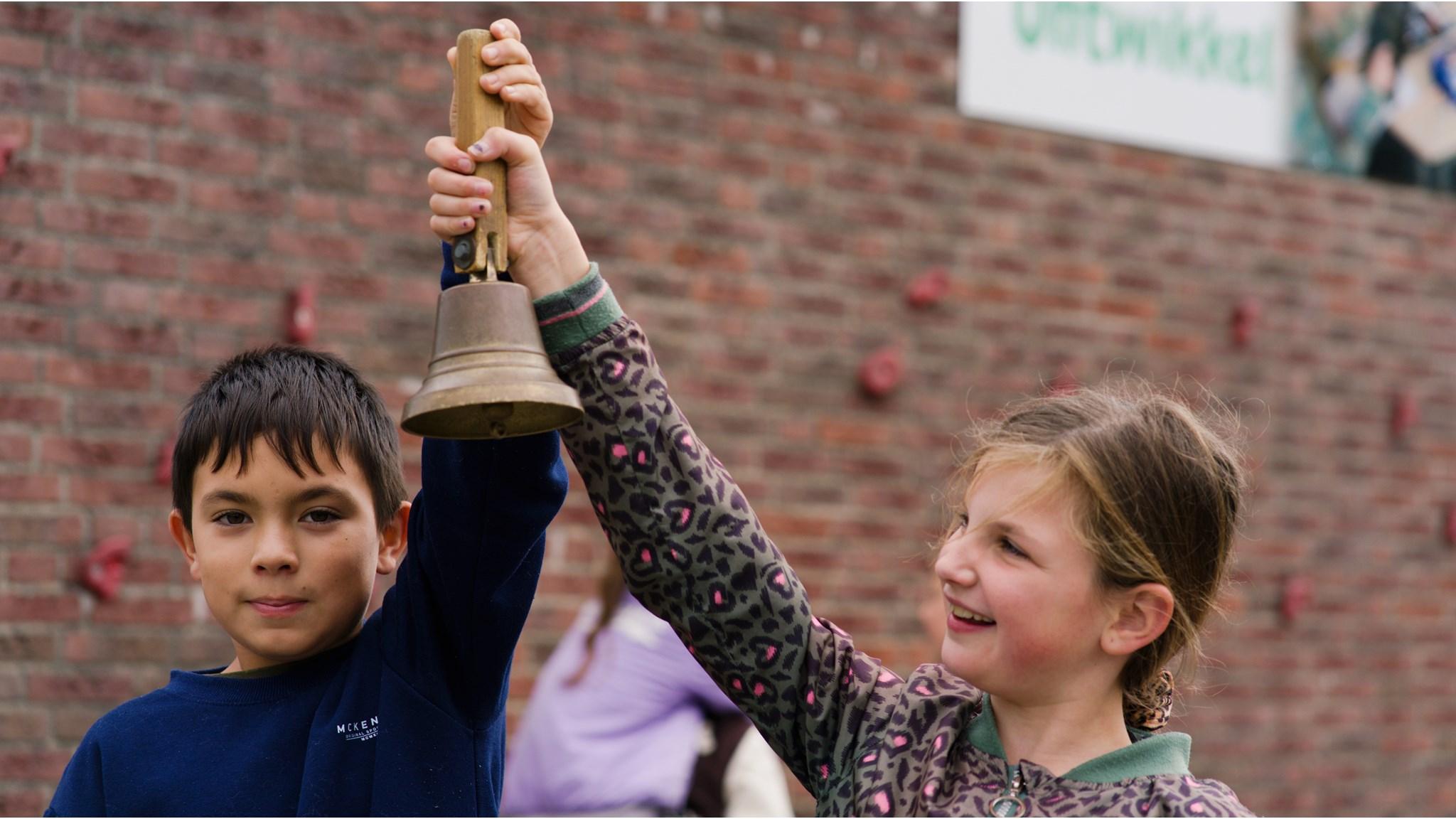 Kinderen van Openbare Basisschool Flevosprong in Dronten vieren een moment met een bel op het schoolplein. Kinderen van Openbare Basisschool Flevosprong in Dronten vieren een moment met een bel op het schoolplein.