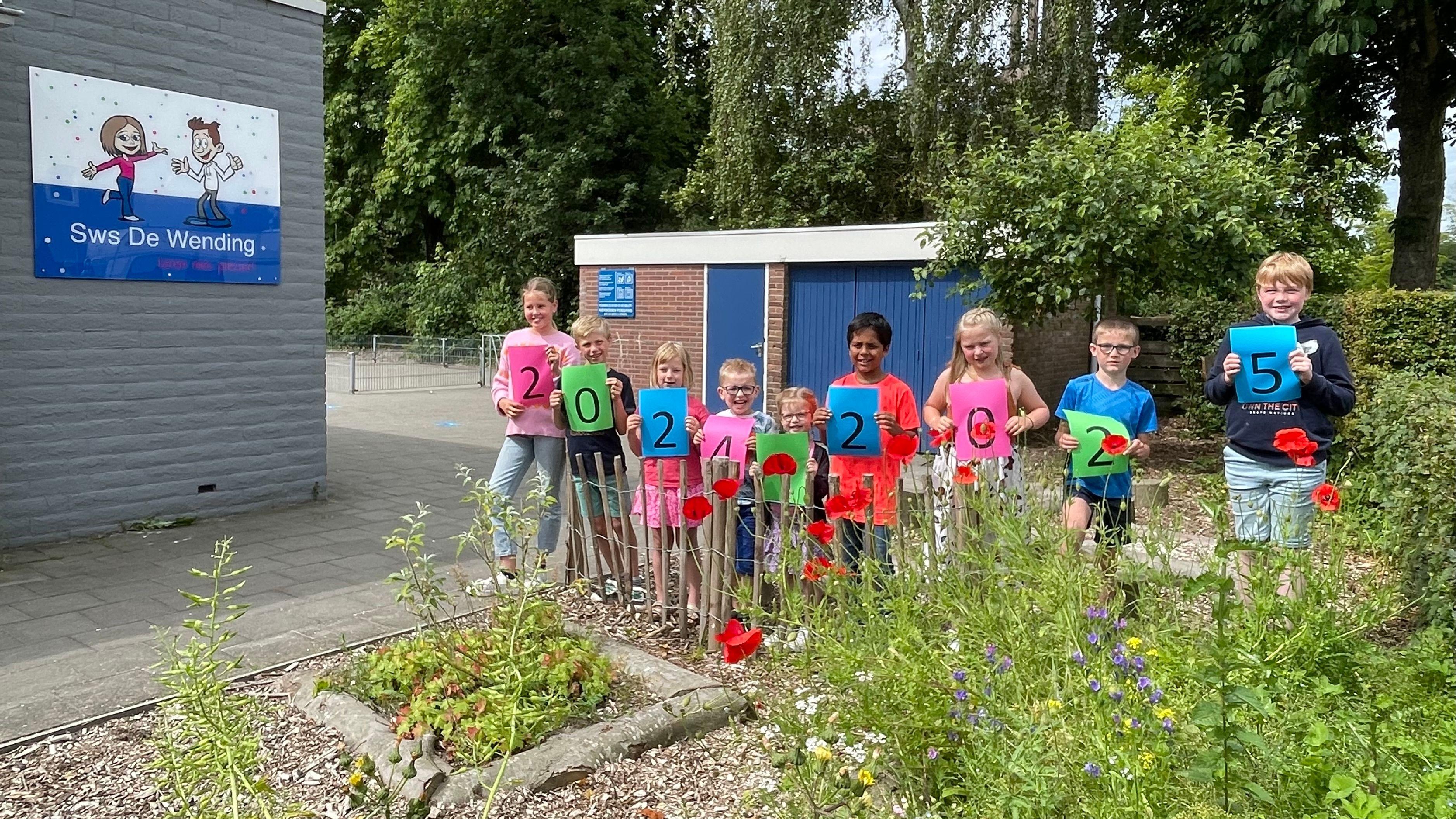 Kinderen van Sws De Wending in Bant tonen cijfers voor het jaar 2025 op het schoolplein. Kinderen van Sws De Wending in Bant tonen cijfers voor het jaar 2025 op het schoolplein.