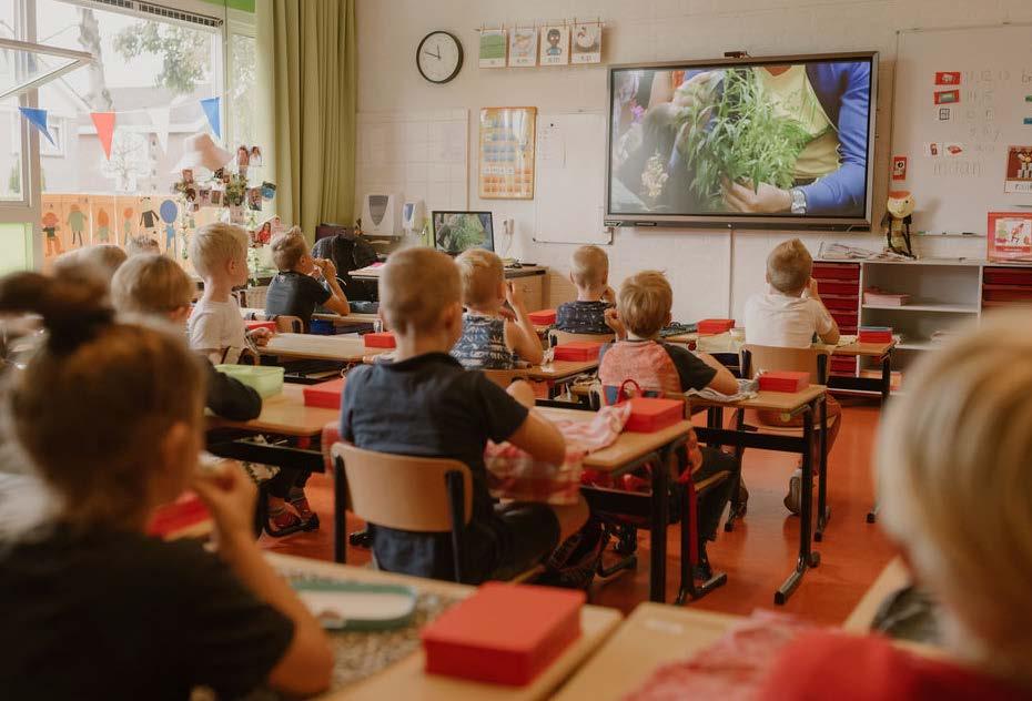 Kinderen zitten in een klaslokaal van Christelijke Basisschool de Roerganger in Heerenveen, terwijl ze aandachtig naar een presentatie op het scherm kijken. Kinderen zitten in een klaslokaal van Christelijke Basisschool de Roerganger in Heerenveen, terwijl ze aandachtig naar een presentatie op het scherm kijken.
