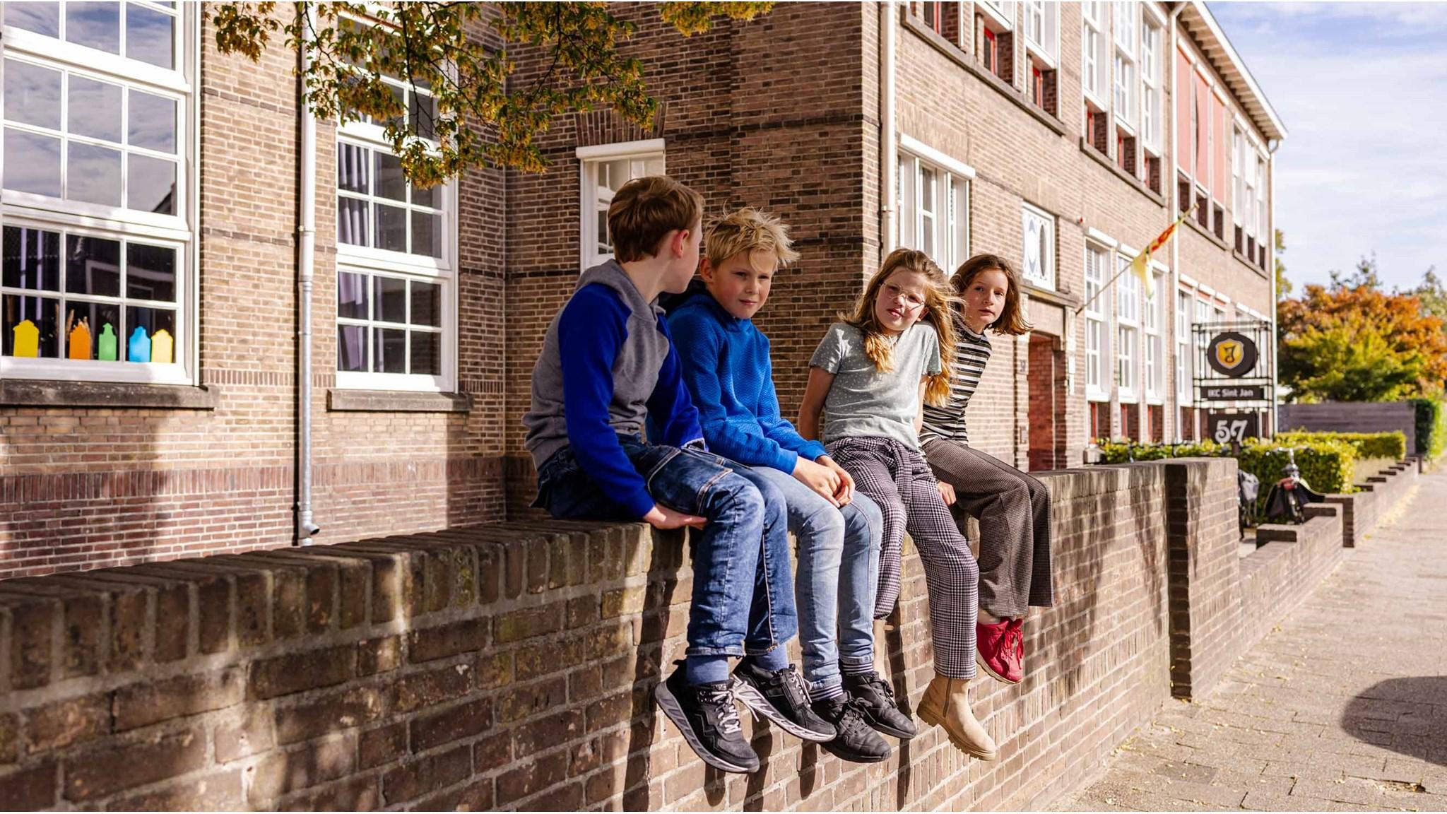 Kinderen zitten op de muur van het schoolplein van IKC Sint Jan in Hengelo. Kinderen zitten op de muur van het schoolplein van IKC Sint Jan in Hengelo.