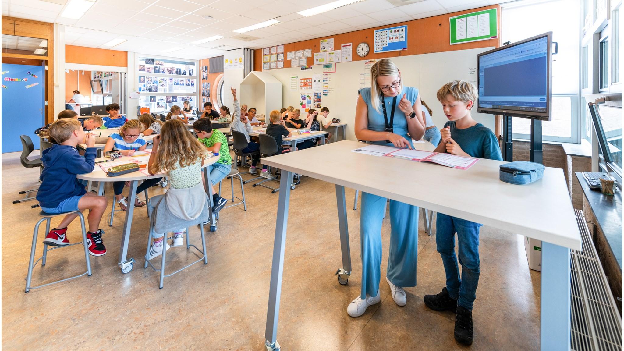 Klasse in Kindcentrum Amby, Maastricht, met leerlingen die werken aan opdrachten en een lerares die hen ondersteunt. Klasse in Kindcentrum Amby, Maastricht, met leerlingen die werken aan opdrachten en een lerares die hen ondersteunt.