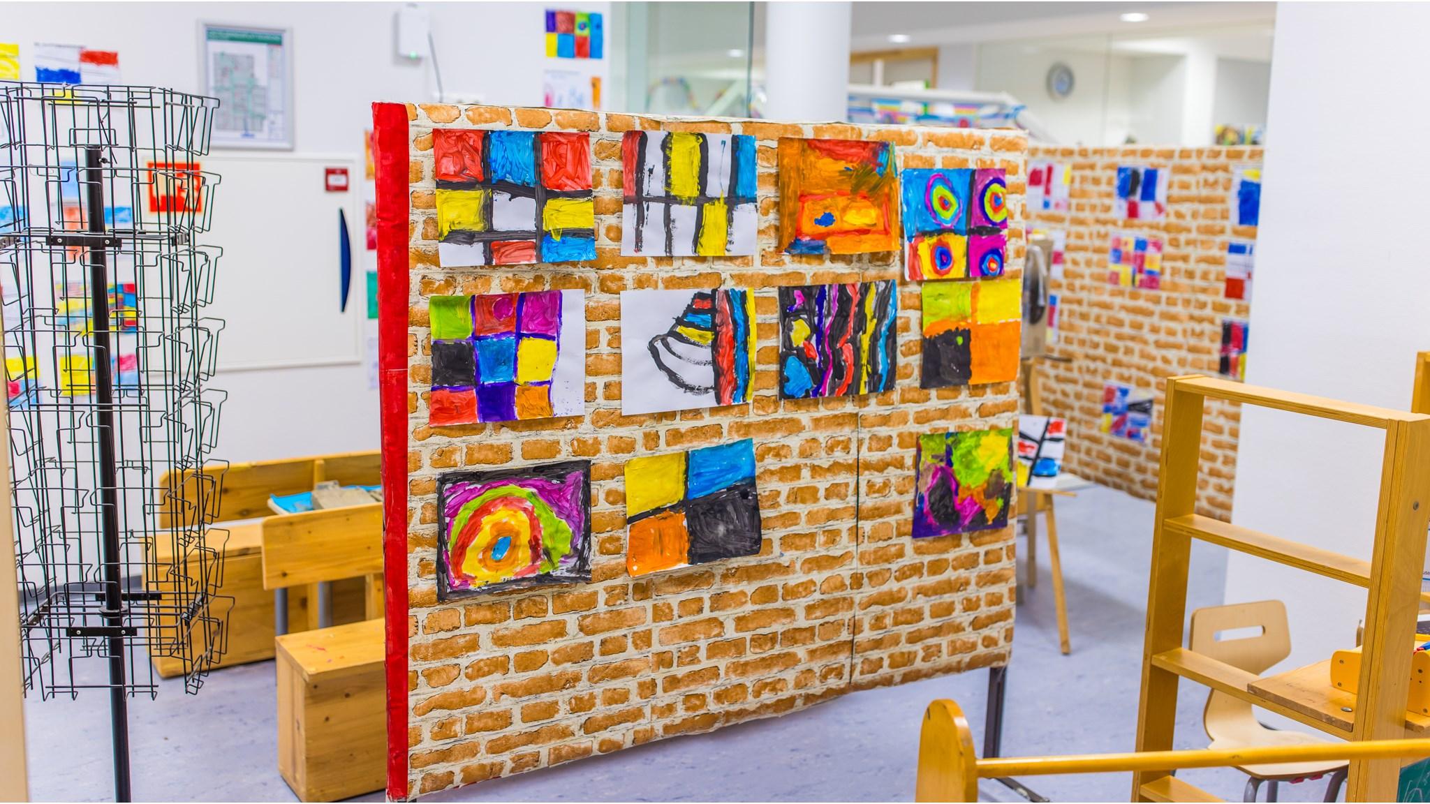 Kunstwerken van leerlingen hangen op een muur in Basisschool De Triangel in Grijpskerk.