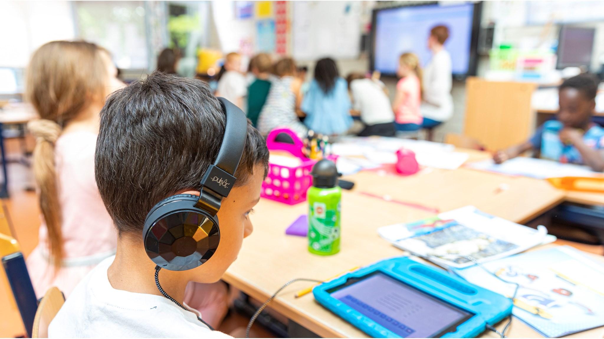 Leerling met een tablet en koptelefoon in de klas van Openbare basisschool Digitalis in Almere. Leerling met een tablet en koptelefoon in de klas van Openbare basisschool Digitalis in Almere.