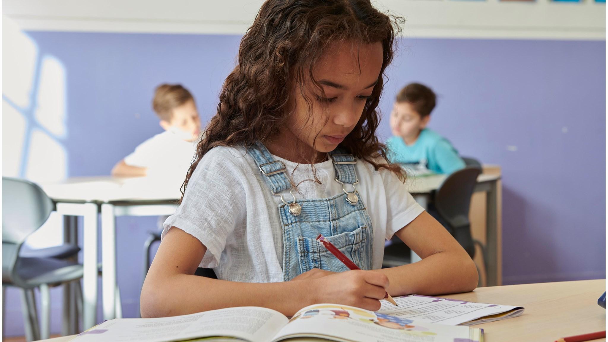 Leerling van de Cruquiusschool in Haarlem schrijft geconcentreerd in de klas. Leerling van de Cruquiusschool in Haarlem schrijft geconcentreerd in de klas.