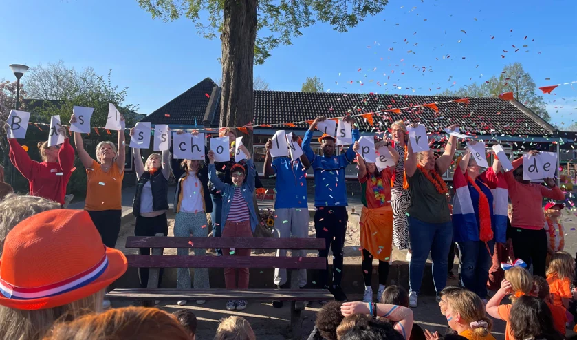 Leerlingen en personeel van Basisschool Wisperweide in Weesp vieren een feestelijke gelegenheid op het schoolplein. Leerlingen en personeel van Basisschool Wisperweide in Weesp vieren een feestelijke gelegenheid op het schoolplein.