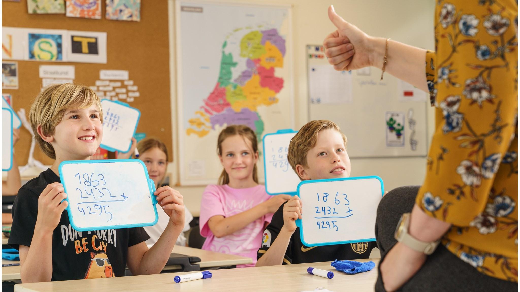 Leerlingen in de klas van CKC De Rietzanger in Eelderwolde tonen hun antwoorden op whiteboards.