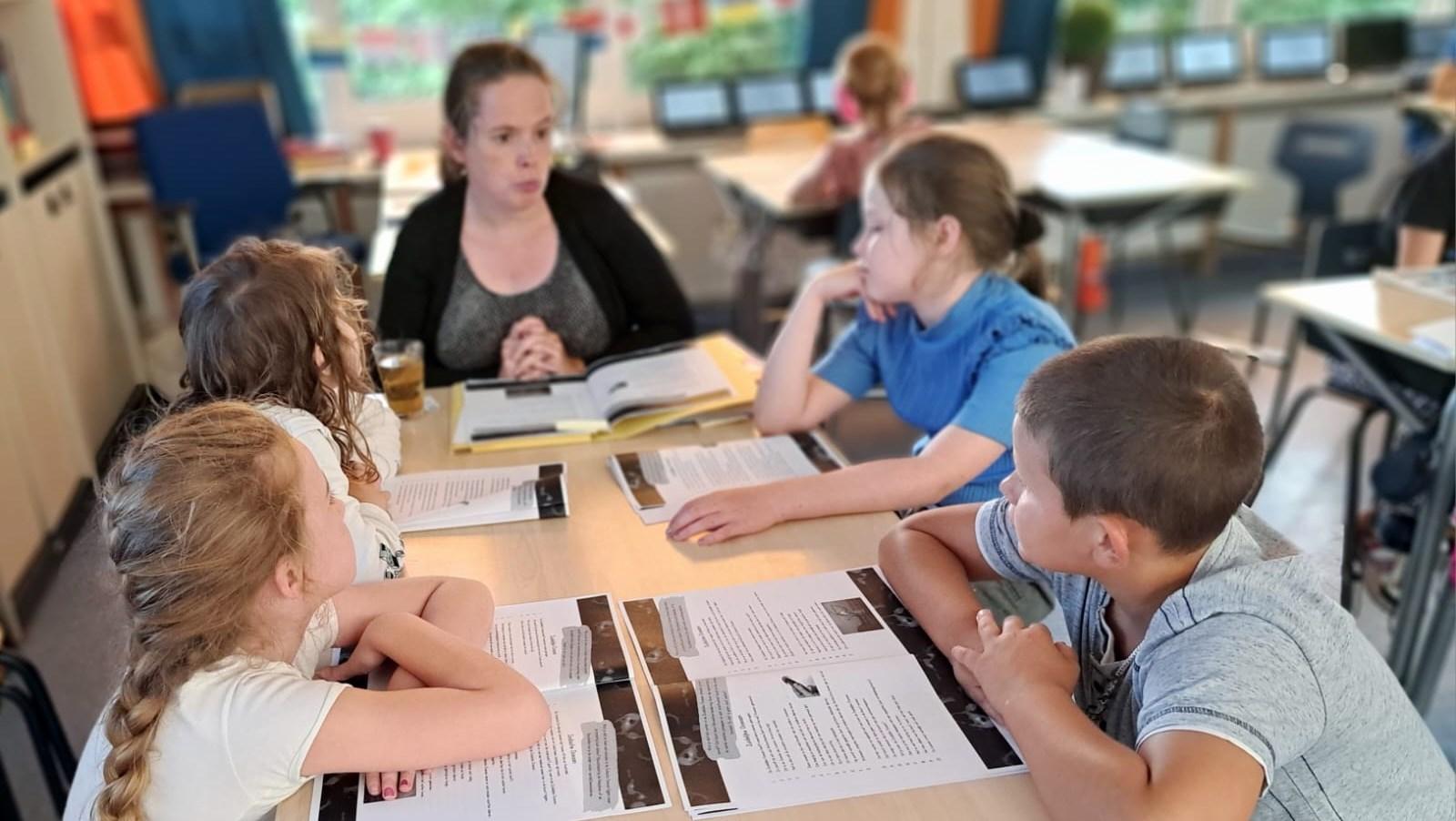 Leerlingen in gesprek met hun leerkracht aan tafel, Oranje Nassauschool, Geldermalsen. Leerlingen in gesprek met hun leerkracht aan tafel, Oranje Nassauschool, Geldermalsen.