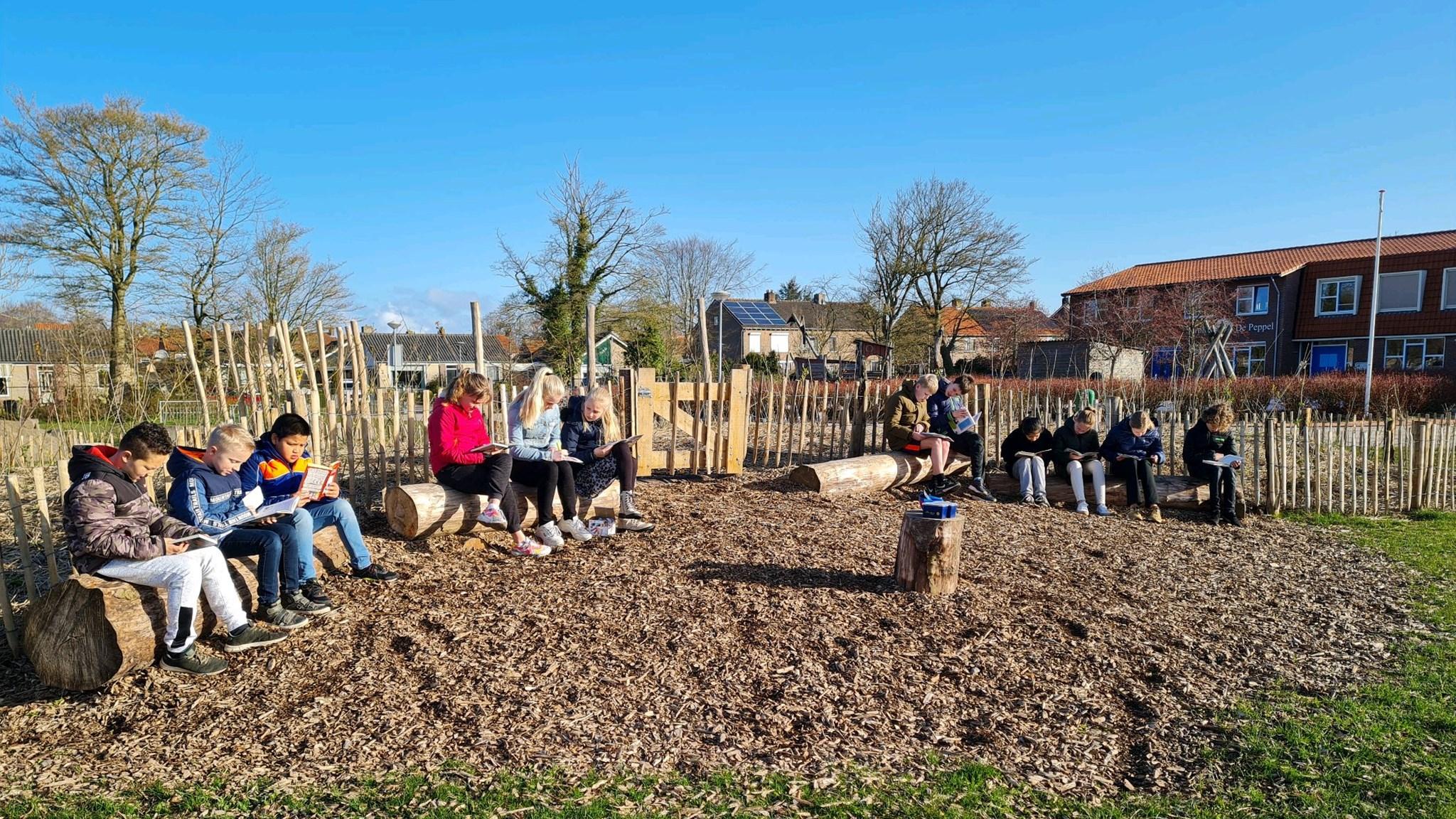 Leerlingen van basisschool De Wegwijzer in Middenmeer genieten van een zonnige dag op het schoolplein terwijl ze lezen. Leerlingen van basisschool De Wegwijzer in Middenmeer genieten van een zonnige dag op het schoolplein terwijl ze lezen.