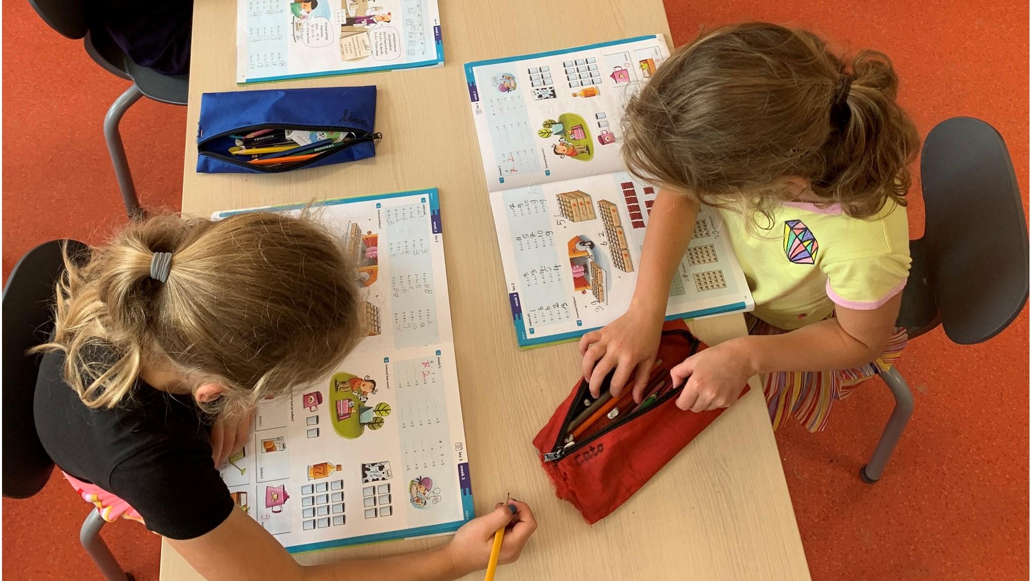 Leerlingen van Basisschool De Weiert in Arcen zijn bezig met hun schoolwerk aan een tafel. Leerlingen van Basisschool De Weiert in Arcen zijn bezig met hun schoolwerk aan een tafel.