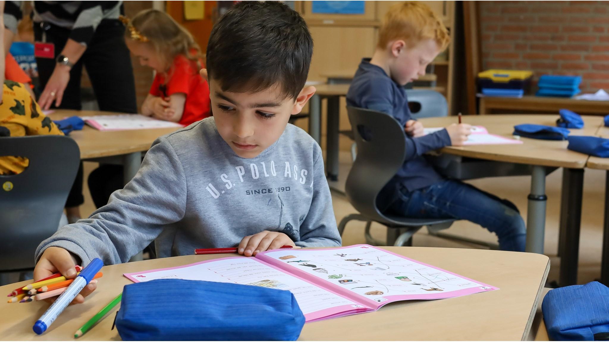 Leerlingen van Basisschool Het Palet in Haaksbergen zijn actief aan het werk met kleurpotloden en lesmateriaal aan hun tafels. Leerlingen van Basisschool Het Palet in Haaksbergen zijn actief aan het werk met kleurpotloden en lesmateriaal aan hun tafels.