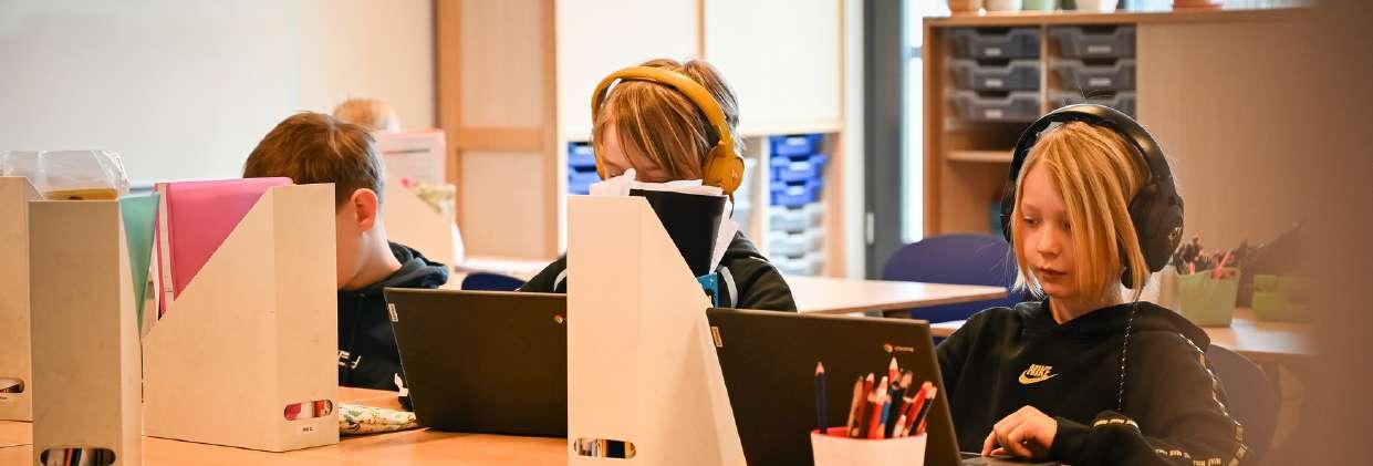 Leerlingen van Basisschool M Wiegman in Bergen (Noord-Holland) werken geconcentreerd achter laptops met hoofdtelefoons. Leerlingen van Basisschool M Wiegman in Bergen (Noord-Holland) werken geconcentreerd achter laptops met hoofdtelefoons.