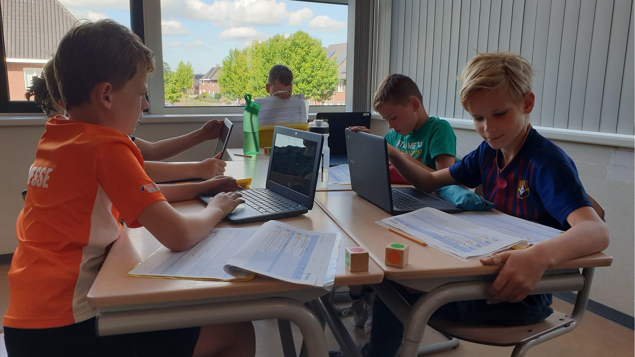 Leerlingen van Basisschool Maria in Erp zijn bezig met hun schoolwerk aan een tafel. Leerlingen van Basisschool Maria in Erp zijn bezig met hun schoolwerk aan een tafel.