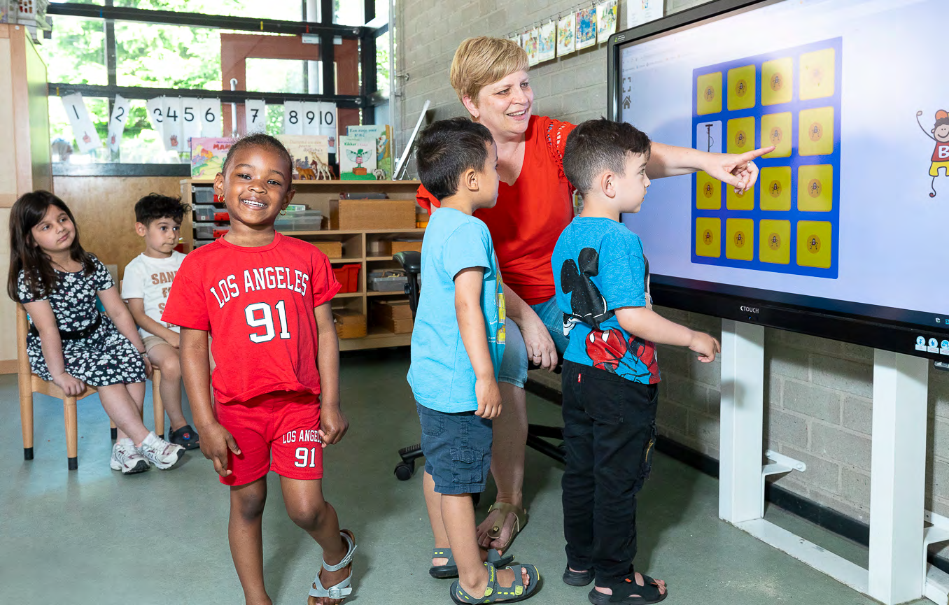 Leerlingen van CBS Mozaïek in Rotterdam oefenen samen met de juf aan een interactieve smartboard.