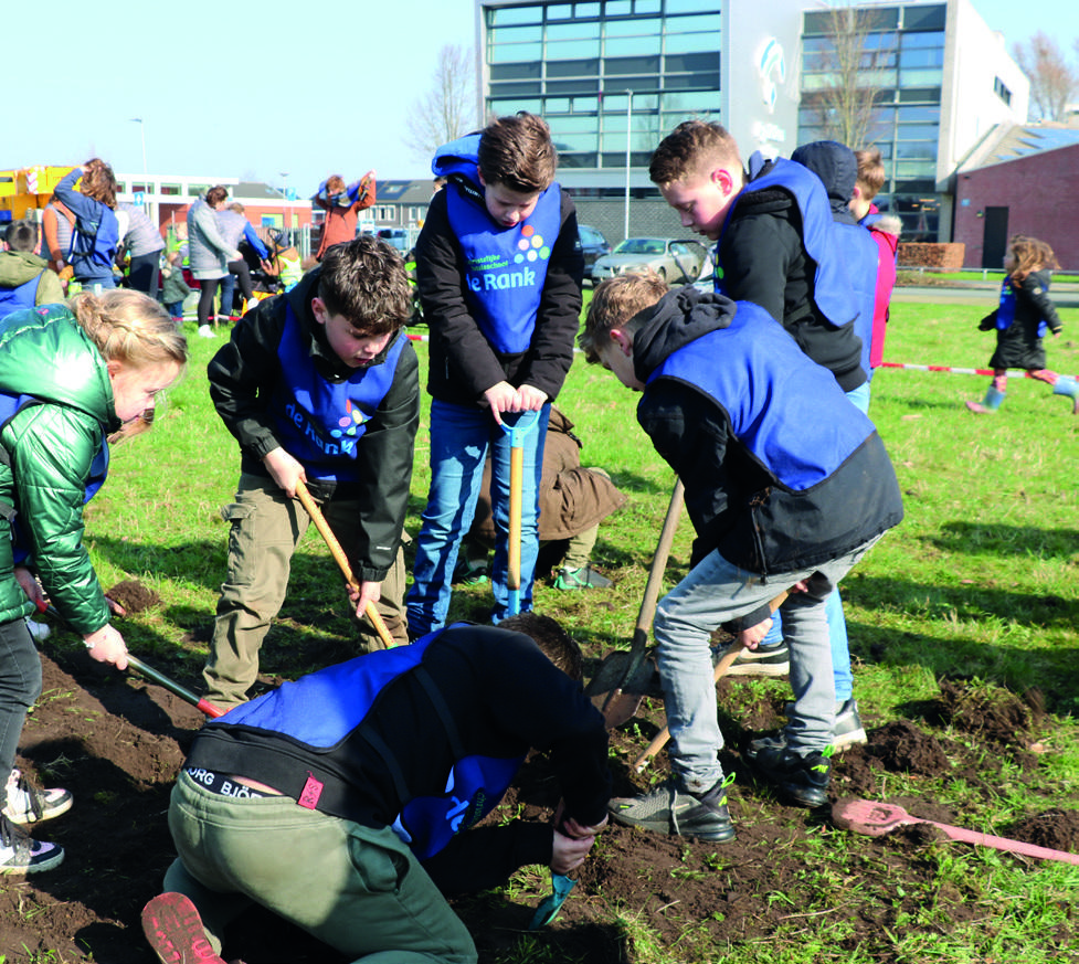 Leerlingen van Christelijke Basisschool De Bron in Wezep werken samen in het schoolplein om de aarde te bewerken.