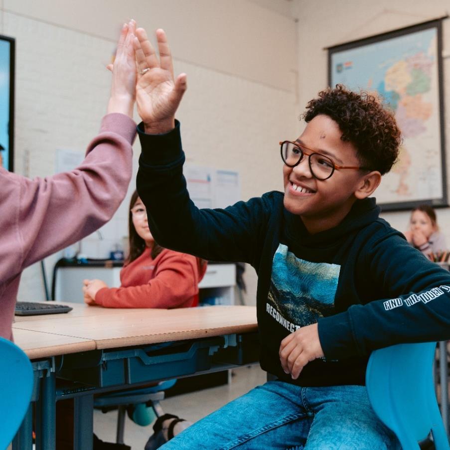 Leerlingen van de Bernardusschool in Den Haag geven elkaar een high five in de klas. Leerlingen van de Bernardusschool in Den Haag geven elkaar een high five in de klas.