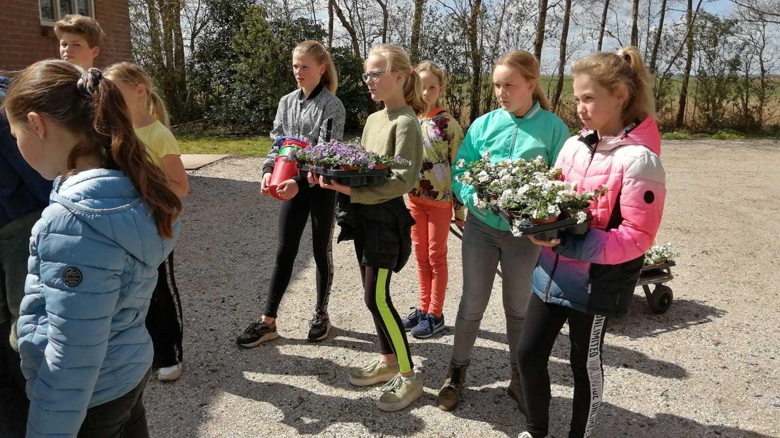 Leerlingen van De Finne in Warten dragen bloemen tijdens een buitenactiviteit. Leerlingen van De Finne in Warten dragen bloemen tijdens een buitenactiviteit.