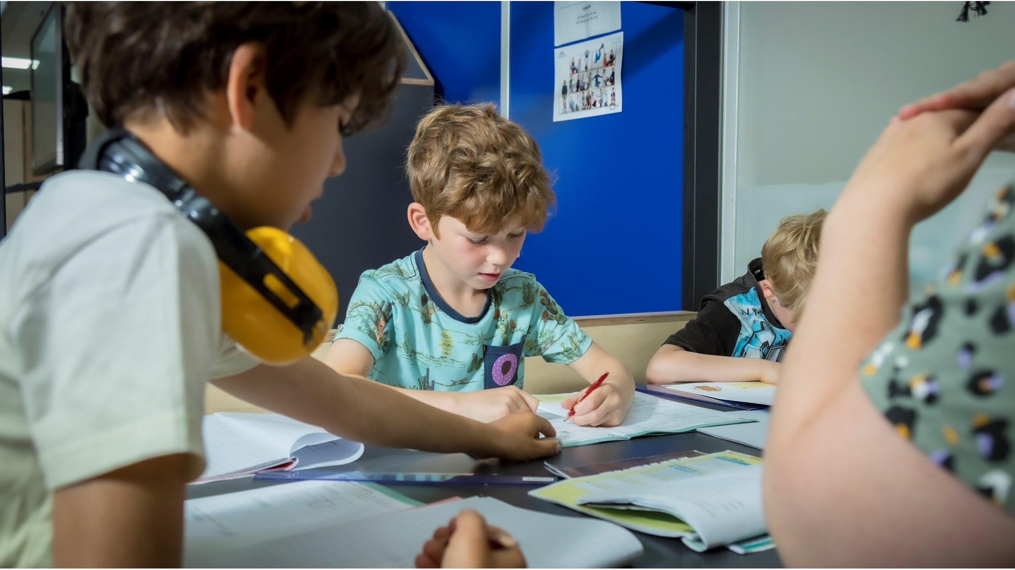 Leerlingen van de Johan Frisoschool in Woerden zijn bezig met hun schoolwerk aan een tafel. Leerlingen van de Johan Frisoschool in Woerden zijn bezig met hun schoolwerk aan een tafel.