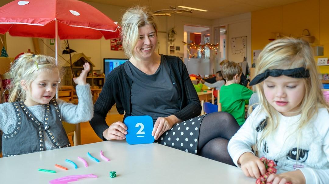 Leerlingen van de Lucebertschool in Bergen (Noord-Holland) leren spelenderwijs met een docente aan een tafel. Leerlingen van de Lucebertschool in Bergen (Noord-Holland) leren spelenderwijs met een docente aan een tafel.