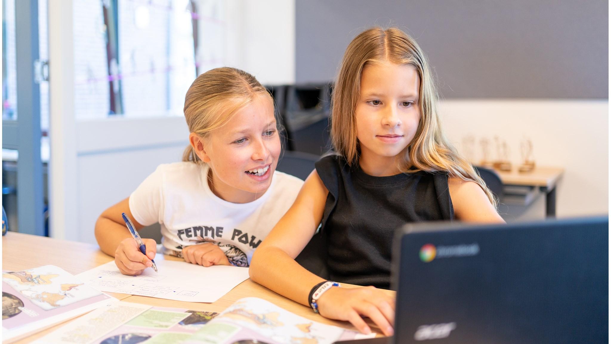 Leerlingen van de Mariaschool in Pijnacker werken samen aan een opdracht met een laptop. Leerlingen van de Mariaschool in Pijnacker werken samen aan een opdracht met een laptop.