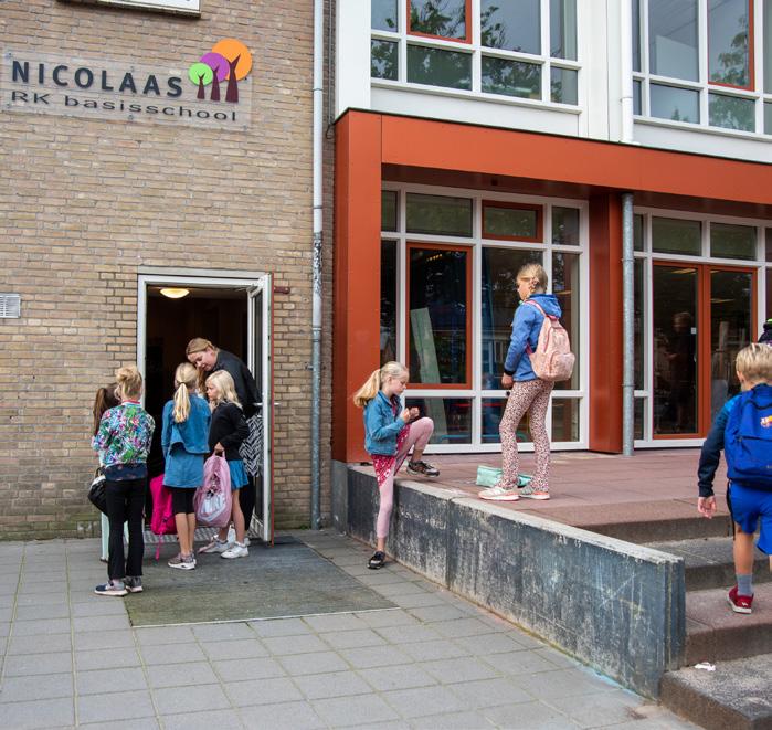 Leerlingen van de Nicolaas Basisschool in Schalkhaar staan bij de ingang van de school en op de stoep. Leerlingen van de Nicolaas Basisschool in Schalkhaar staan bij de ingang van de school en op de stoep.