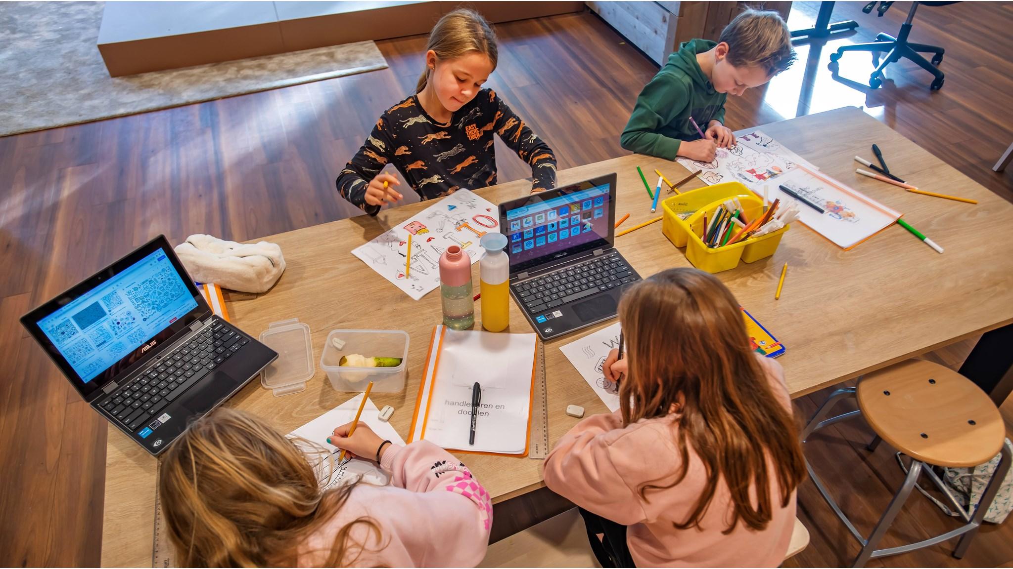 Leerlingen van De Zandberg in Breda zijn aan het tekenen en leren aan een grote tafel met laptops en creatieve materialen. Leerlingen van De Zandberg in Breda zijn aan het tekenen en leren aan een grote tafel met laptops en creatieve materialen.