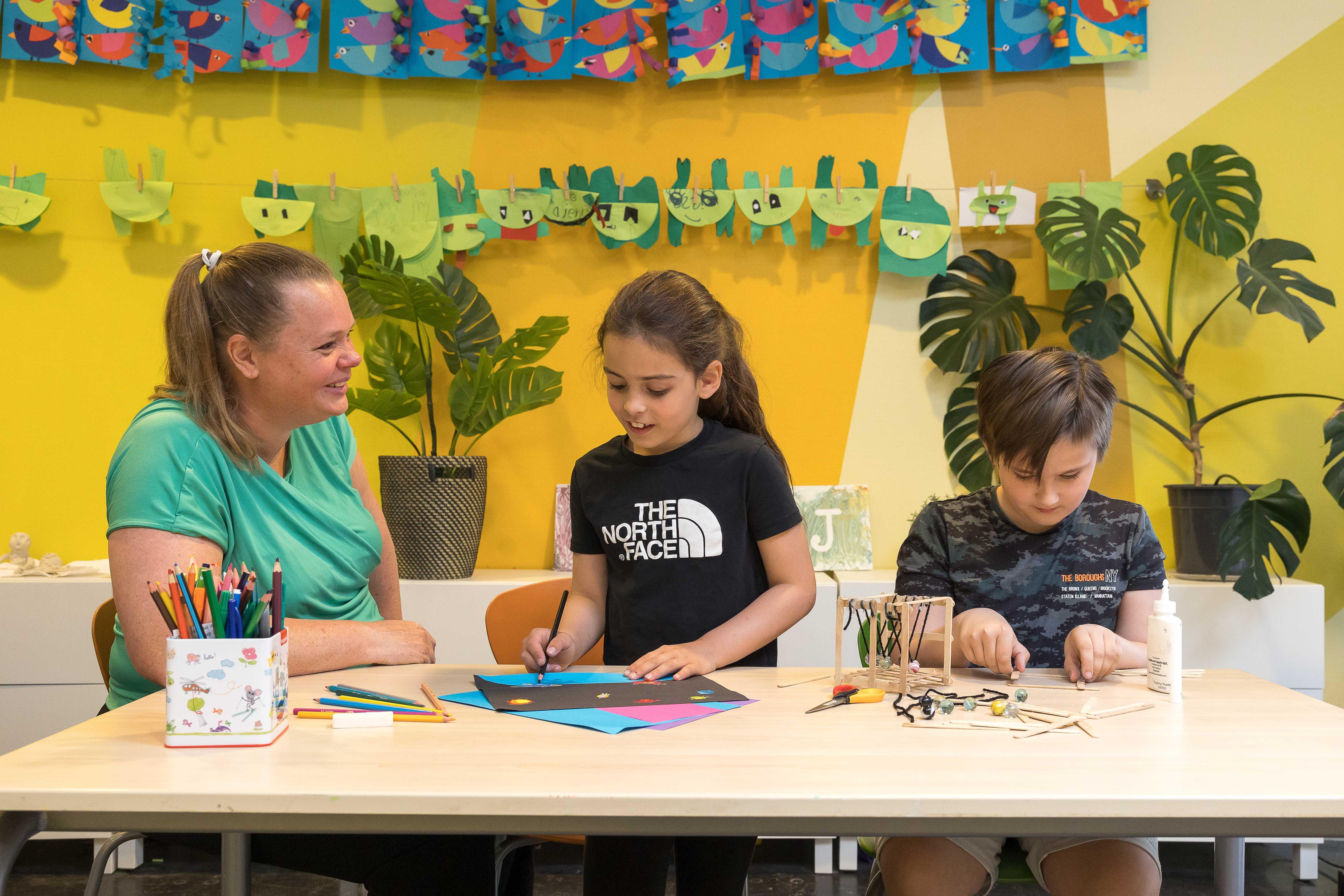 Leerlingen van IKC De Achtsprong in Zoetermeer zijn creatief aan het knutselen met een docente in een kleurrijke lesruimte. Leerlingen van IKC De Achtsprong in Zoetermeer zijn creatief aan het knutselen met een docente in een kleurrijke lesruimte.