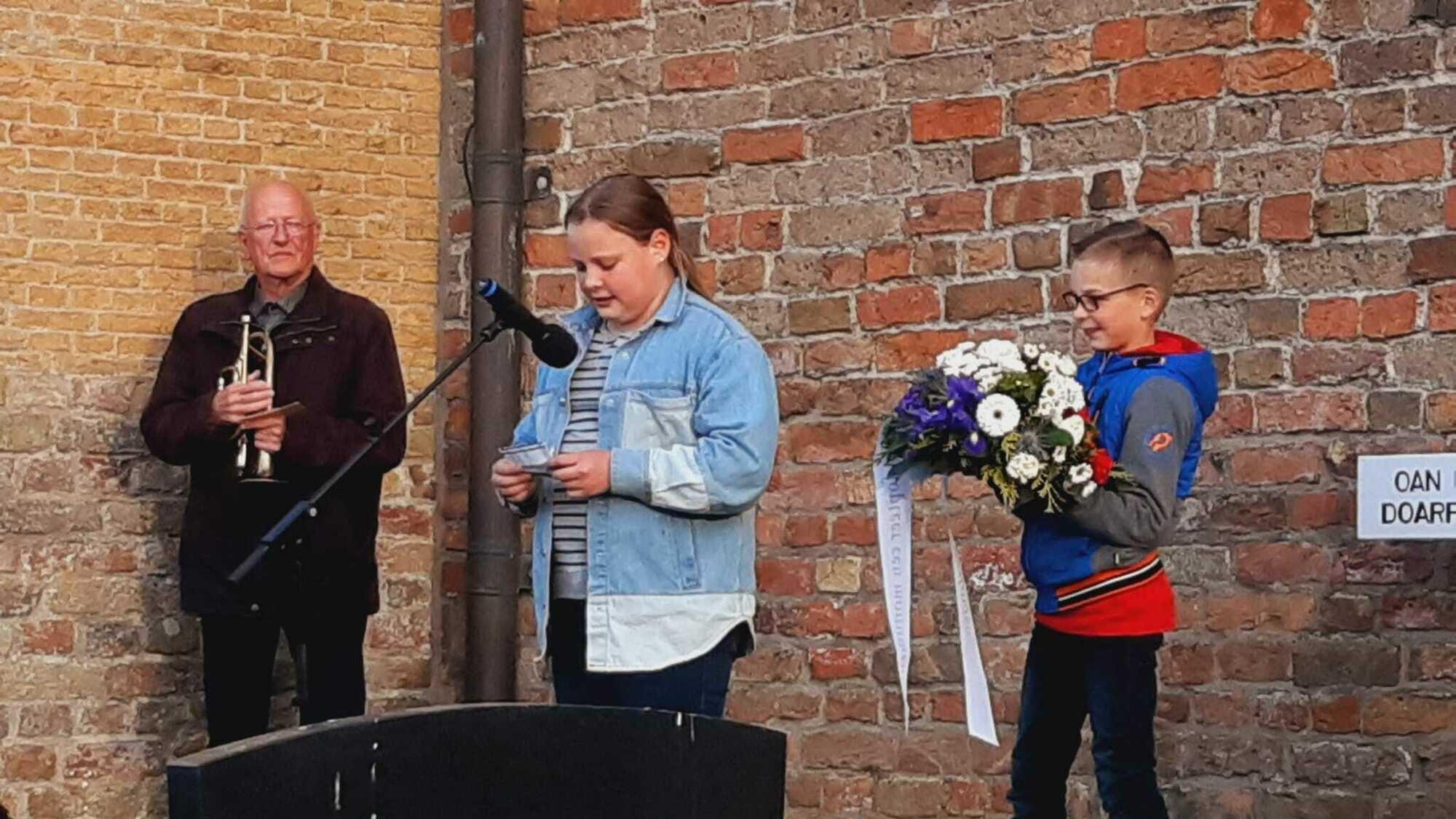 Leerlingen van IKC De Flambou in Oosterbierum geven een presentatie tijdens een evenement met bloemen en een muzikant op de achtergrond. Leerlingen van IKC De Flambou in Oosterbierum geven een presentatie tijdens een evenement met bloemen en een muzikant op de achtergrond.
