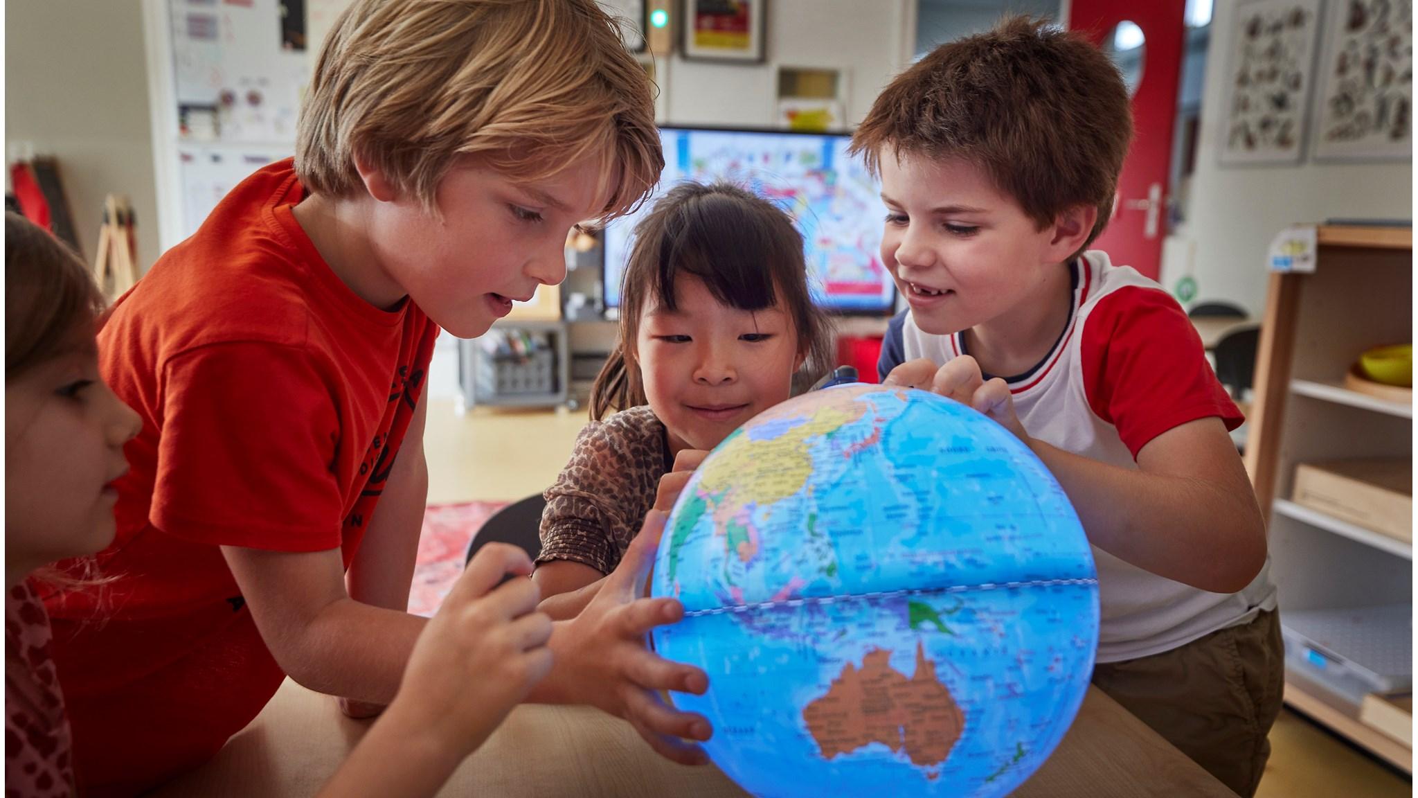 Leerlingen van KBS Stepping Stones in Utrecht verkennen samen een wereldbol in de klas. Leerlingen van KBS Stepping Stones in Utrecht verkennen samen een wereldbol in de klas.