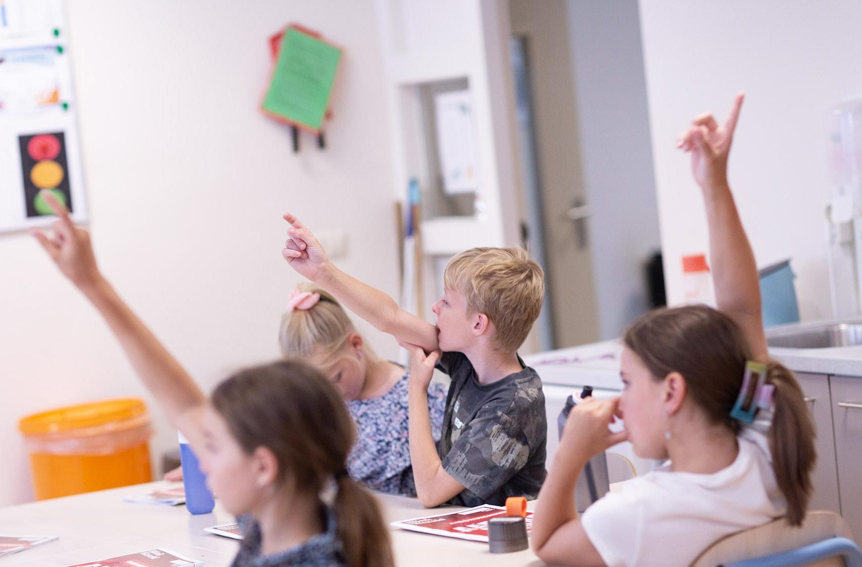 Leerlingen van Kindcentrum de KAS in Waddinxveen steken hun handen op tijdens de les. Leerlingen van Kindcentrum de KAS in Waddinxveen steken hun handen op tijdens de les.