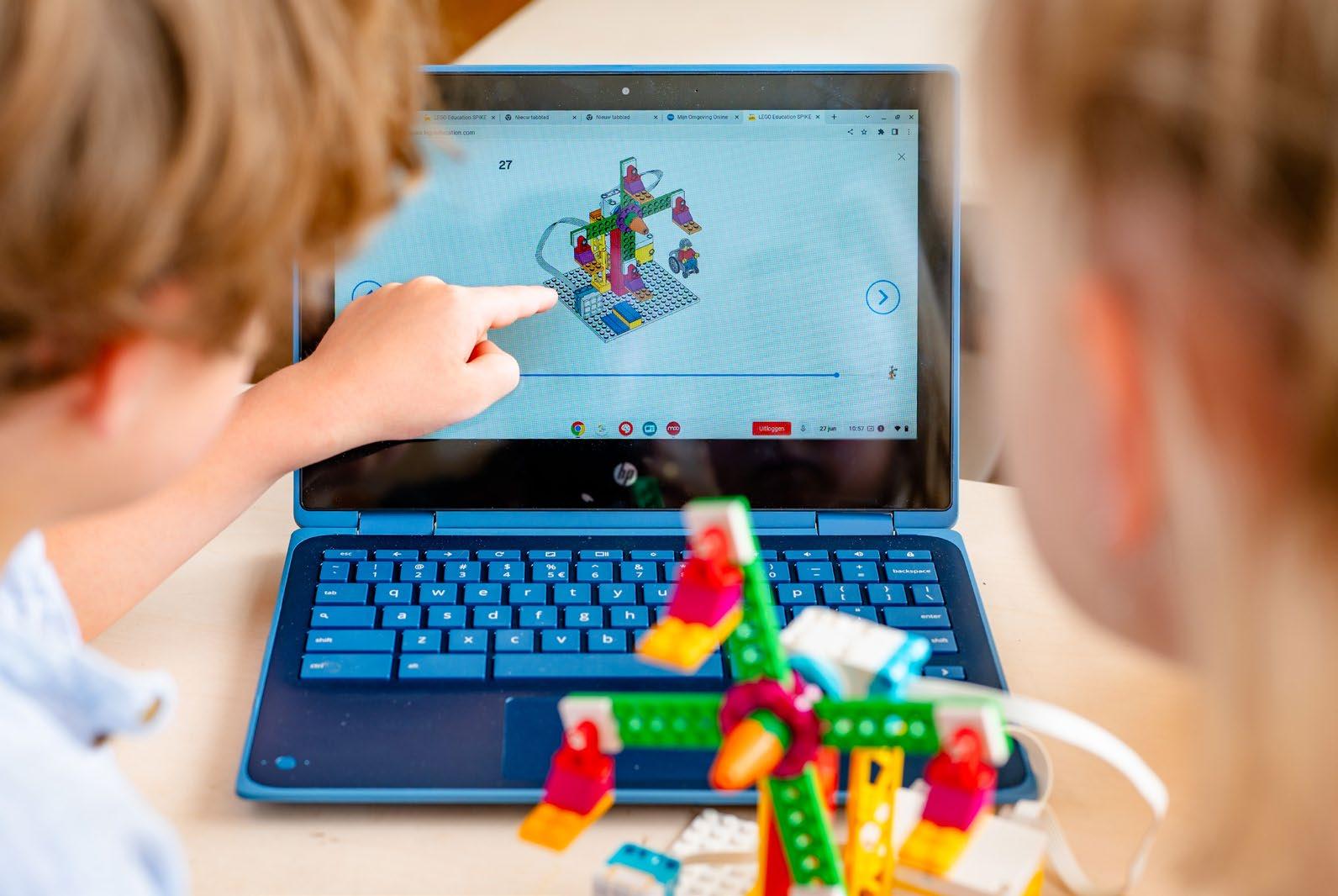 Leerlingen van Kindcentrum De Morgenster in Zwolle werken samen aan een LEGO-project met behulp van een laptop.