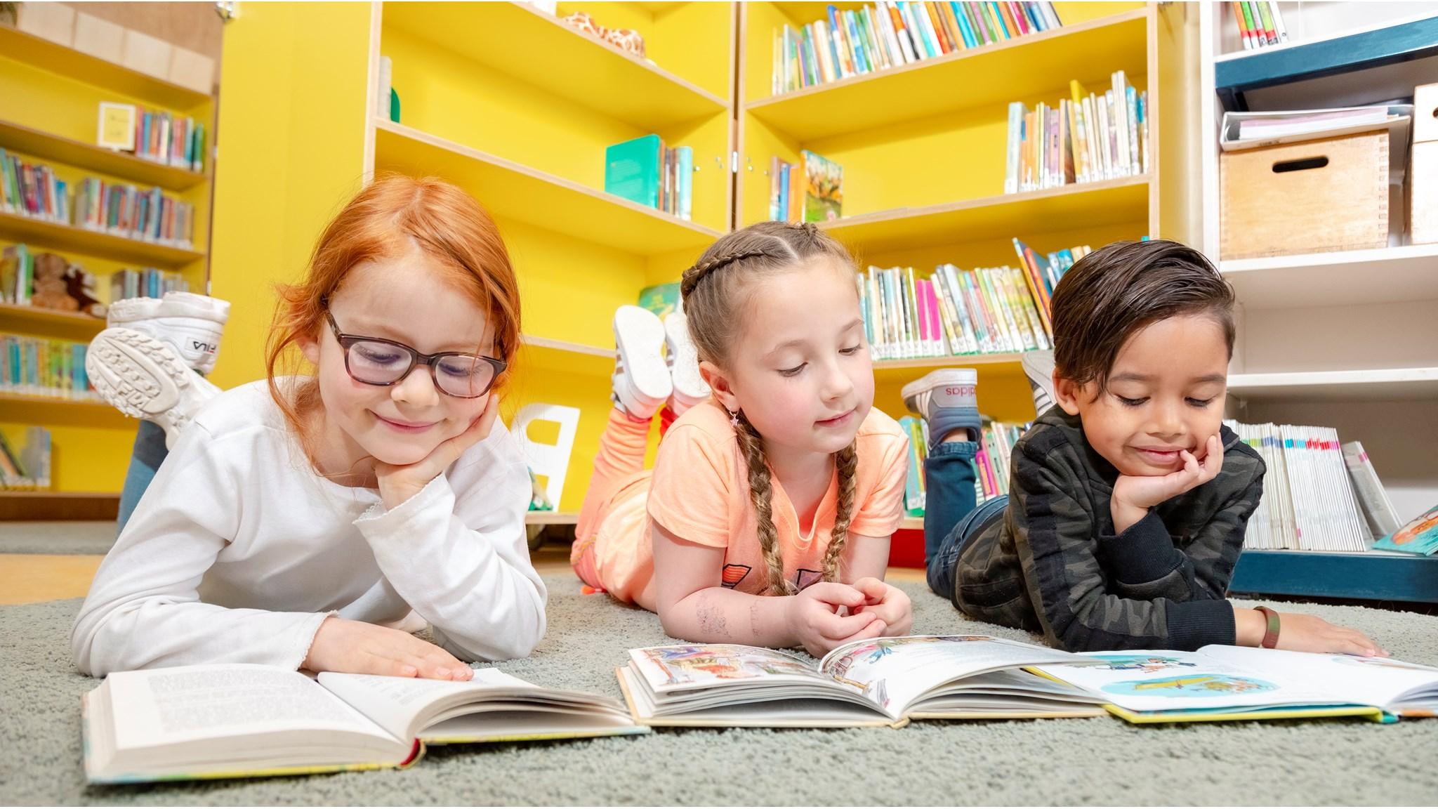 Leerlingen van Max Havelaar Kindcentrum in Delft genieten van het lezen van boeken op de vloer in de bibliotheek. Leerlingen van Max Havelaar Kindcentrum in Delft genieten van het lezen van boeken op de vloer in de bibliotheek.