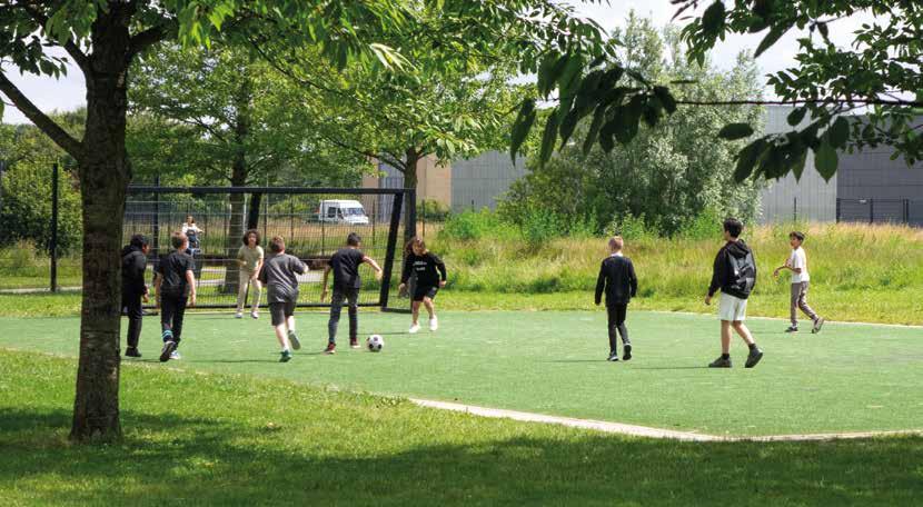 Leerlingen van Obs De Optimist in Hoofddorp spelen voetbal op het schoolplein.