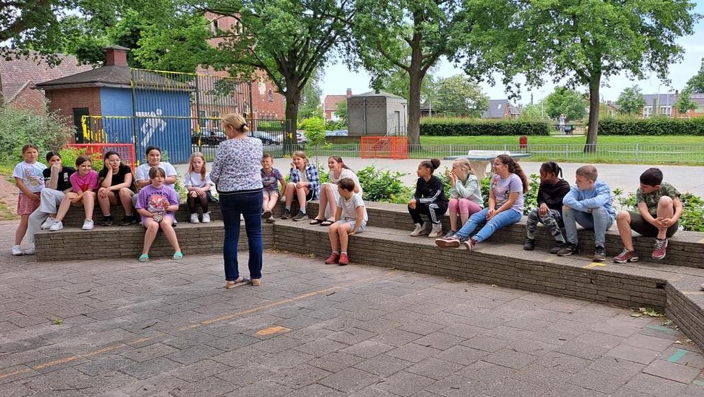 Leerlingen van obs Willem Wilmink in Enschede luisteren naar een docente op het schoolplein. Leerlingen van obs Willem Wilmink in Enschede luisteren naar een docente op het schoolplein.