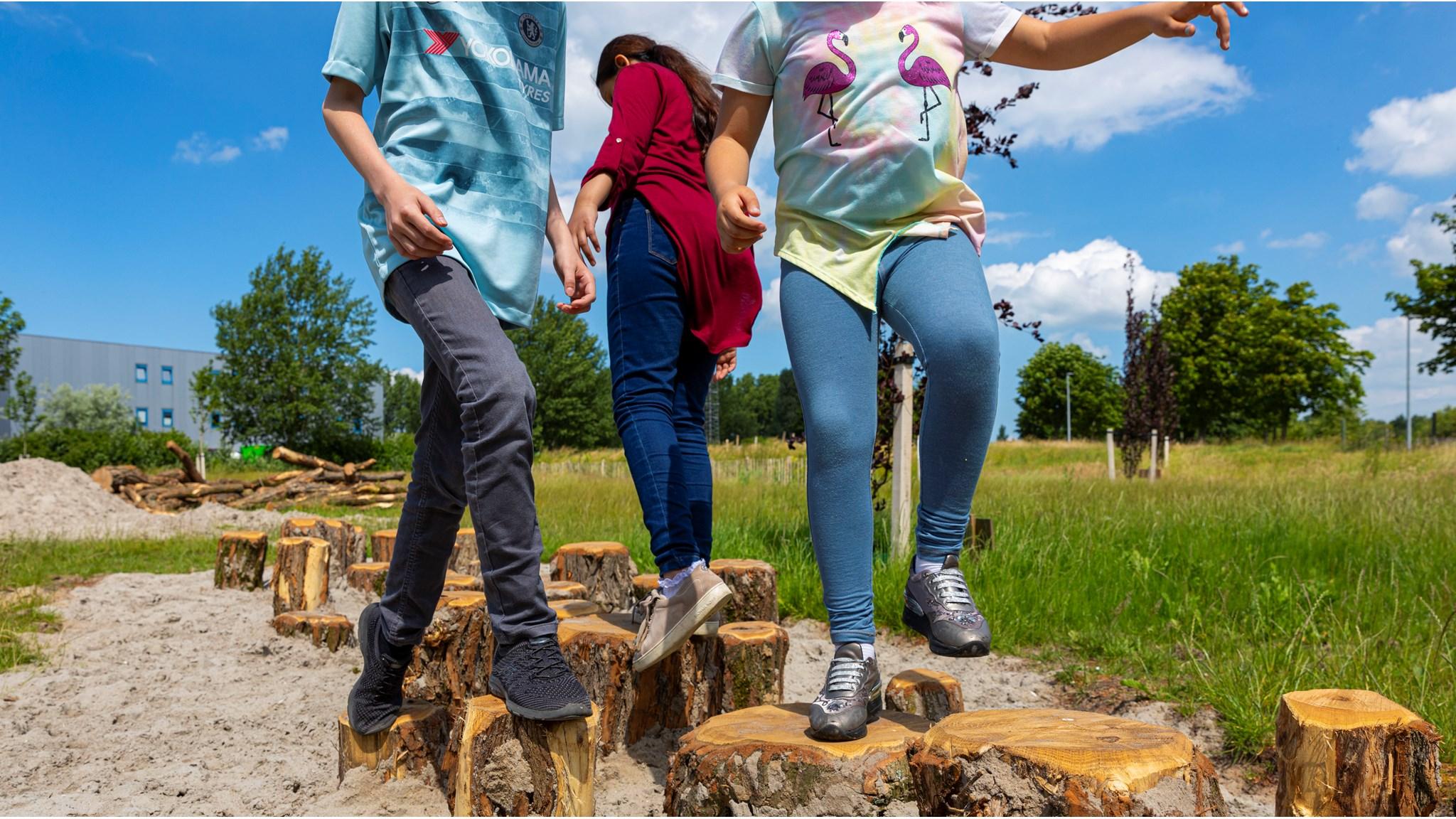 Leerlingen van Openbare basisschool Digitalis in Almere spelen en balanceren op houten stammetjes op het schoolplein. Leerlingen van Openbare basisschool Digitalis in Almere spelen en balanceren op houten stammetjes op het schoolplein.