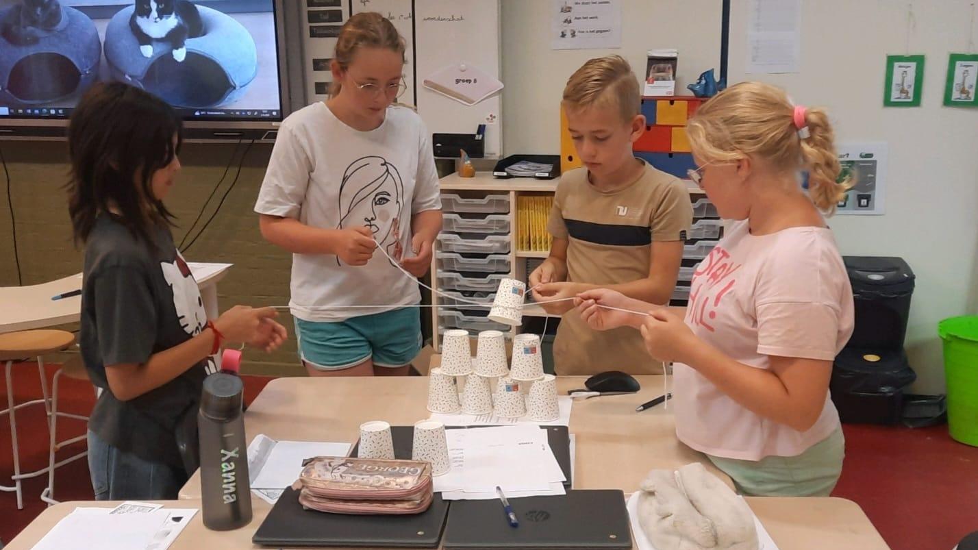 Leerlingen van Openbare basisschool 't Kompas in Dedemsvaart werken samen aan een opdracht met bekers en touwen. Leerlingen van Openbare basisschool 't Kompas in Dedemsvaart werken samen aan een opdracht met bekers en touwen.